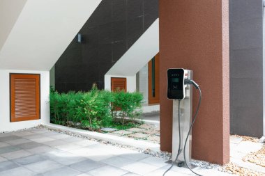 Progressive green energy-powered charging station concept for electric vehicle connected to home charging station at the garage or backyard. Eco friendly rechargeable car powered by clean energy.