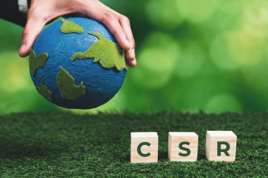 Kâğıt küre ve CSR sembolü küpüyle el ele tutuşan bir iş adamı. CO2 emisyon politikası olmayan çevre dostu yeşil ve etik iş şirketi. Yeşil toplumdan sorumlu kurumsal toplum. Değiştir