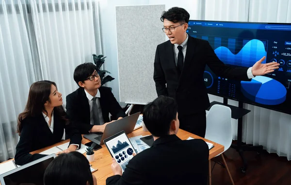 Confidence and asian businessman give presentation on financial analyzed by business intelligence in dashboard report to other people in board room meeting to promote harmony in workplace.