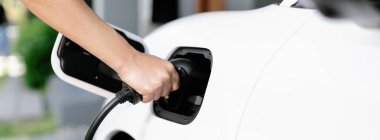 Progressive concept of hand insert an emission-free power connector to the battery of electric vehicle at home. Electric vehicle charging via cable from charging station to EV car battery