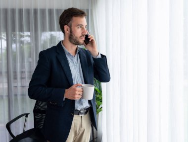 Çalışkan iş adamı, modern ofiste güvenilir bir şekilde müşteriye ikna edici satış çağrıları yapıyor. Ofis çalışanı telefonda konuşuyor ve iş arkadaşlarıyla iş görüşmesi yapıyor. Varlık