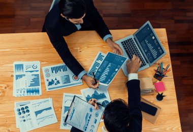 Üst düzey analist ekibi dijital torpido gözündeki finansal verileri tartışıyor, tabloyu analiz ediyor ve tahta masa arkasındaki veri bilimi yazılımının grafiklerini inceliyor. İş zekası ve Fintech. Coşkulu