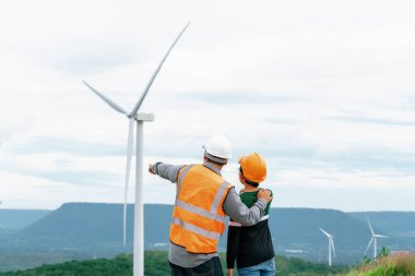 Oğluyla birlikte kırsal kesimdeki bir tepenin tepesinde ya da dağda bir rüzgar çiftliğinde mühendis. Yenilenebilir ve sürdürülebilir enerjinin gelecekteki üretimi için yenilikçi bir ideal. Rüzgar türbininden enerji üretimi.