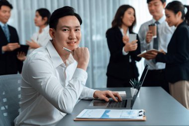 Portrait of focus young successful confident male manager, executive wearing business wear in harmony office arm crossed with blurred meeting background of colleagues, office worker.