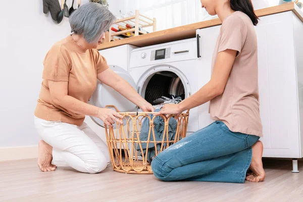 stock image Daughter and mother working together to complete their household chores near the washing machine in a happy and contented manner. Mother and daughter doing the usual tasks in the house.