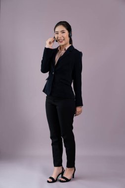 Çekici tüm vücut Asyalı kadın çağrı merkezi operatörü. Mutlu yüzlü, boş alanda iş ilanı veren, kişiselleştirilebilir arka planda resmi takım elbise ve kulaklık takan. Coşkulu.