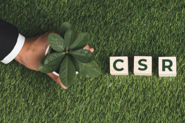 Üst düzey bir işadamı elinde CSR 'ı sembolize eden küplü bir saksı tutuyor. Karbondioksit salınımı politikası olmayan etik ve çevre dostu yeşil iş. Yeşil toplumdan sorumlu kurumsal bir sosyal sorumluluk üstlenin. Değiştir
