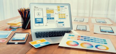 Dizüstü bilgisayar ekranında web ya da mobil uygulama UI UX için dijital ve kağıt kablo tasarımları. Beyin fırtınası ve tasarım uygulama çerçevesi için geliştirici çalışma alanının panoramik görüntüsü. İnceleyin