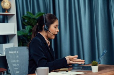 Bilgisayarında mikrofon ve kulaklıkla Asyalı çağrı merkezi çalışıyor. Kadın operatör istisnai müşteri hizmetleri sunar. Destek veren çağrı merkezi ajanı, müşteriye soruşturmada yardım ediyor. Coşkulu.