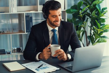 Erkek çağrı merkezi operatörü ya da telesales temsilcisi ofis masasında otururken kulaklık takıyor ve müşteri desteği sağlayan ya da ikna edici satış yapan müşteriyle sohbet ediyor. coşkulu