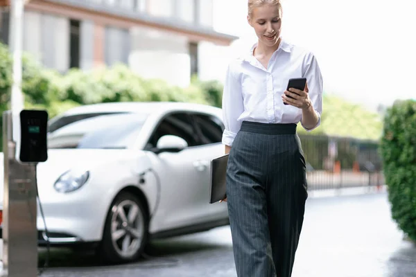 Businesswoman Using Tablet Walking While Recharging Her Electric Vehicle Charging — 스톡 사진