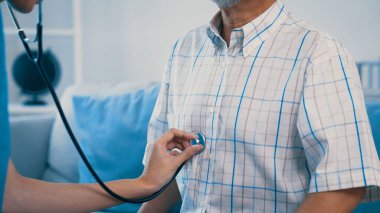 Caring young female doctor performing osteopathy treatment for a contented senior patient. At-home medical treatment for an Asian senior patient, joint pain treatment, medical service for seniors.