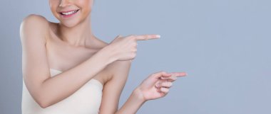 Mükemmel makyajlı, göz kamaştırıcı güzel bir kadın. Temiz cilt, telif alanı izole edilmiş arka planı işaret ediyor. Cilt ürünleri reklamının el hareketi konseptiyle belirlenen promosyon.