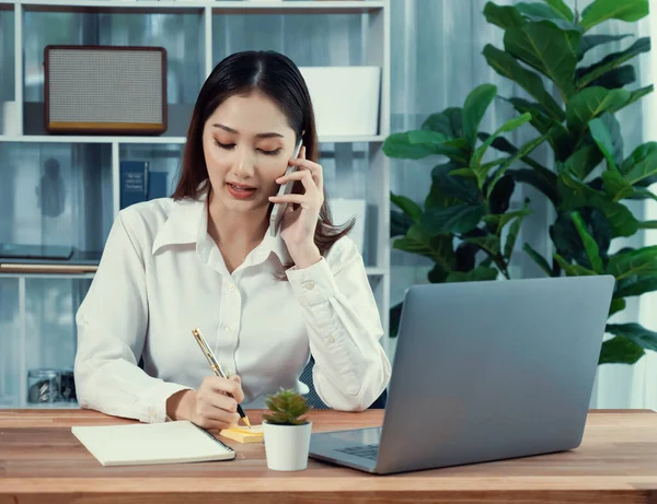 若い熱狂的なビジネスマンの女性は ビジネスコールで話をし マルチタスクオフィスの女性として彼女のラップトップにメモを書きます お客様と電話で会話しながら業務を執筆する女性社員 — ストック写真