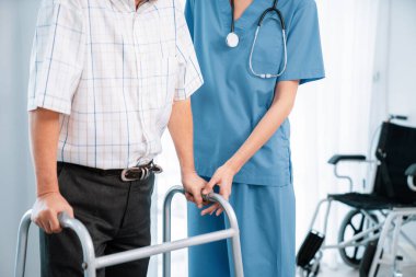 Physiotherapist assists her contented senior patient on folding walker. Recuperation for elderly, seniors care, nursing home.