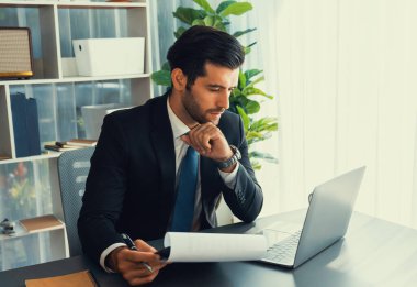 Modern ofis masasındaki modern profesyonel iş adamı çalışmak ve notlar yazmak için dizüstü bilgisayar kullanıyor. Ofisinde bilgisayar defteri üzerinde çalışan çalışkan bir ofis çalışanı. coşkulu