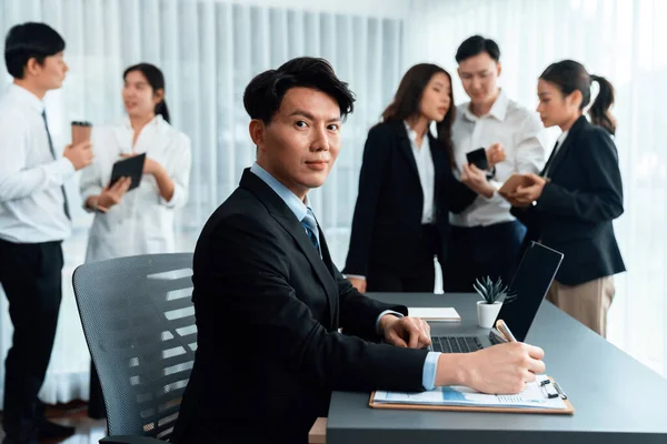 Portrait of focus young successful confident male manager, executive wearing business wear in harmony office arm crossed with blurred meeting background of colleagues, office worker.