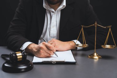 Adalet sembolleri, tokmak çekiç ve terazinin avukatın bulanık arkaplanına odaklanması ya da hukuk sisteminin dürüstlüğü ve adilliği için yasal belgeyi masasında imzalaması. denge