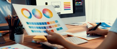 Grafik tasarımcısı, modern dijital stüdyo işyerinde profesyonel grafik ekibiyle benzersiz bir tasarım yaparken bilgisayar dizüstü bilgisayar ve grafik çizim kalemi üzerinde çalışır. Panorama çekimi. İnceleyin