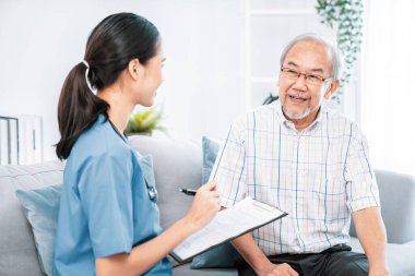 A young female doctor inquires about personal information of a contented senior at home. Medical care for the elderly, elderly illness, and nursing homes, home care.