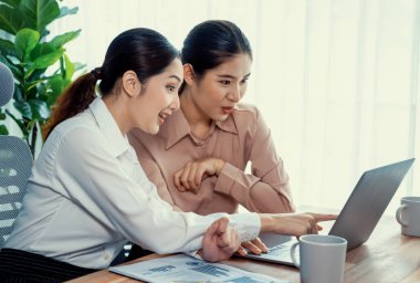 Modern ofis çalışma alanında iş birliği yapan iki genç ofis çalışanı, modern ofis çalışanı olarak profesyonelliklerini sergileyerek, dizüstü bilgisayarda tartışıyorlar ve birlikte çalışıyorlar. Coşkulu.