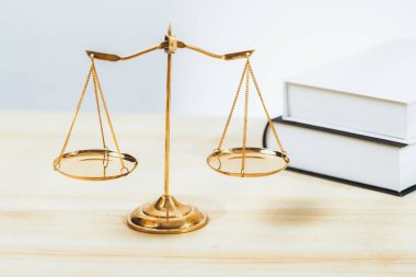 Hukuk fakültesinde adalet ve hukuki sembol olarak masanın üzerinde parlak altın dengeli bir terazi ve hukuk kitabı vardı. Avukat ve avukatın adil ve eşitlik kararı için terazi uygulayın. denge