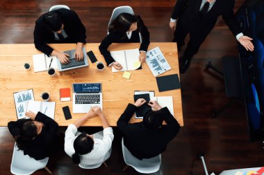 Top view manager or office worker give presentation in harmony conference room to business colleague, BI data dashboard on screen and pile of financial analyzed data reports on meeting table.