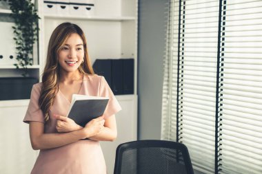 Young competent office lady, intern, secretary holding a log in office room. Concept of various career for office working. Concept of diverse office careers.