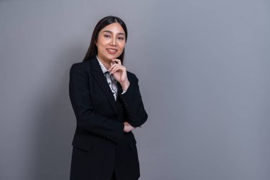 Tecrit edilmiş arka planda profesyonel kıyafetle poz veren kendine güvenen genç Asyalı iş kadını. Başarı sembolü, iyimserlik ve iş tanıtımları ve reklamlar için kurumsal ofis hanımı. Sevinçli.