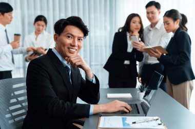 Portrait of focus young successful confident male manager, executive wearing business wear in harmony office arm crossed with blurred meeting background of colleagues, office worker.