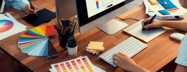 Grafik tasarımcısı, modern dijital stüdyo işyerinde profesyonel grafik ekibiyle benzersiz bir tasarım yaparken bilgisayar dizüstü bilgisayar ve grafik çizim kalemi üzerinde çalışır. Panorama çekimi. İnceleyin