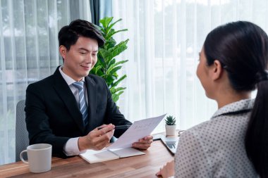 Görüşmeci ve aday arasındaki iş görüşmesi. İK müdürü aday niteliklerini ve özgeçmişli iş başvurusunu soruyor. Başvuru sahibinin işi. Sevinçli.