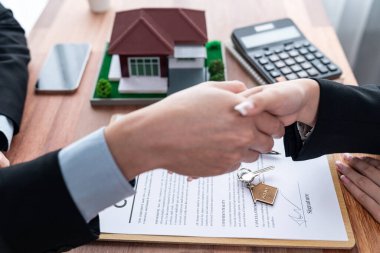 Ev kredisi anlaşması başarılı bir şekilde tokalaşmayla sonuçlandı. Alıcılar ve emlakçılar ev sahipliği anlaşmasını başarı ve memnuniyet duygusuyla kutluyorlar. Sevinçli.