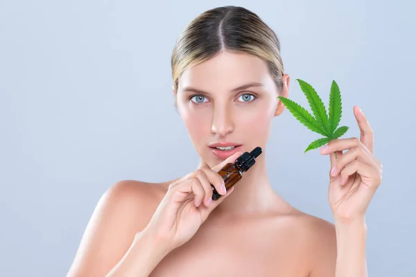 Stock image Alluring portrait of beautiful woman in isolated holding green leaf with marijuan extracted bottle for skincare treatment product. Cannabis CBD oil for cosmetology and beauty concept.