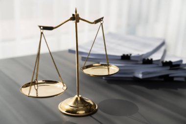 Parlak altın dengeli ölçek ve hukuk bürosundaki yasal kağıt yığını konsept adalet ve hukuki sembol olarak masanın üzerinde. Avukat ve avukatın adil ve eşitlik kararı için terazi uygulayın. denge