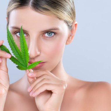 Closeup alluring beautiful woman model portrait holding green leaf as concept for cannabis skincare cosmetic product for skin freshness treatment in isolated background.