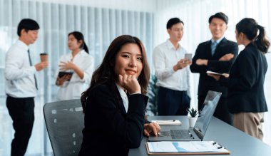 Focus portrait of female manger, businesswoman in the harmony meeting room with blurred of colleagues working together, analyzing financial paper report and dashboard data in background.