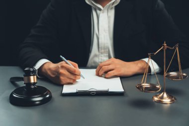 Adalet sembolleri, tokmak çekiç ve terazinin avukatın bulanık arkaplanına odaklanması ya da hukuk sisteminin dürüstlüğü ve adilliği için yasal belgeyi masasında imzalaması. denge