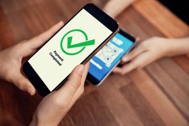 QR kodu parasız ödeme taraması için ekranda gösterilir. Kapalı eller, mobil uygulamadan elektronik işlem yoluyla para aktarmak için akıllı telefonu tutuyor. Hızlı ödeme için barkod teknolojisi. Coşkulu.
