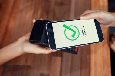 QR kodu parasız ödeme taraması için ekranda gösterilir. Kapalı eller, mobil uygulamadan elektronik işlem yoluyla para aktarmak için akıllı telefonu tutuyor. Hızlı ödeme için barkod teknolojisi. Coşkulu.