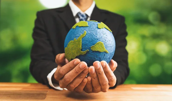 Businessman holds paper earth as symbol of eco environmental awareness for sustainable world using clean energy and zero CO2 emission. Eco-friendly corporate with go green policy to save earth. Alter