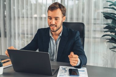 İşadamı ofis masasından sanal ofis toplantısı düzenliyor ve uzaktan çalışanlarla uzak iletişim kurmak için dizüstü bilgisayardaki Webinar uygulamasını kullanarak çevrimiçi video konferansını tartışıyor. Varlık
