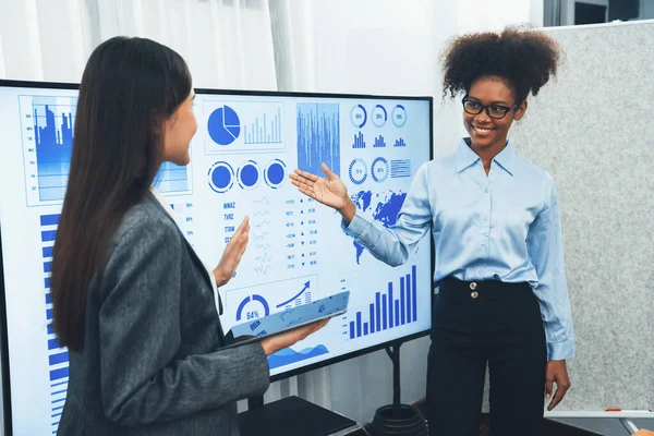 Genç Afrikalı ve Asyalı iş kadınları modern toplantıda TV ekranında veri analiz paneli sunuyorlar. Bir grup iş adamıyla konferans odasında iş sunumu. Uyum