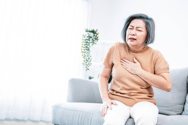 An agonizing elderly woman is experiencing chest pain. Medical attention, senior care service.