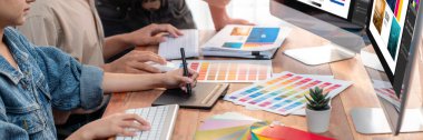 Grafik tasarımcısı, modern dijital stüdyo işyerinde profesyonel grafik ekibiyle benzersiz bir tasarım yaparken bilgisayar dizüstü bilgisayar ve grafik çizim kalemi üzerinde çalışır. Panorama çekimi. İnceleyin