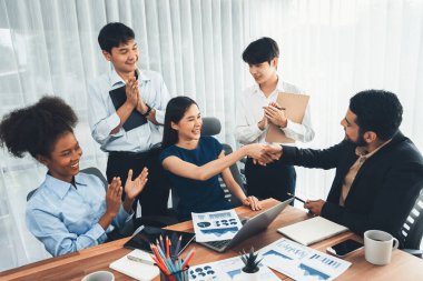 Çeşitli iş arkadaşları başarıyı şirket işyerindeki el sıkışma ve takım çalışmasıyla kutluyor. Çok kültürlü, mutlu profesyonellerden oluşan bir ekip ofiste tokalaşarak birlik oldular. Uyum