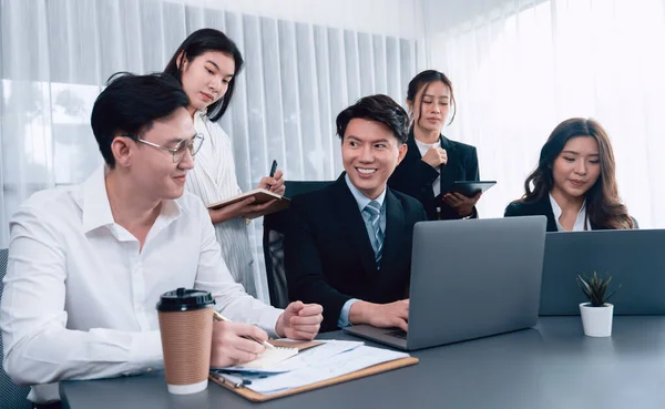 Stock image Harmony in office concept as business people analyzing dashboard paper together in workplace. Young colleagues give ideas at manager desk for discussion or strategy planning about project.