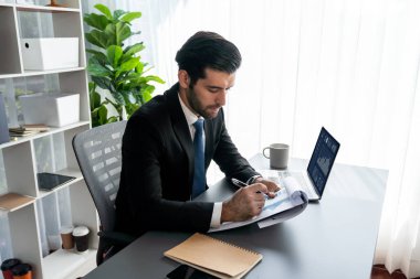 Modern ofis masasındaki modern profesyonel iş adamı çalışmak ve notlar yazmak için dizüstü bilgisayar kullanıyor. Ofisinde bilgisayar defteri üzerinde çalışan çalışkan bir ofis çalışanı. coşkulu