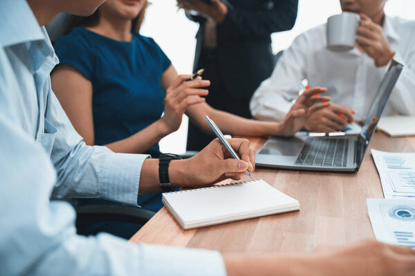 Secretary taking notes on notebook at corporate meeting with group of multiracial business people discussing together in meeting room. Diversity in professional meeting at modern office. Concord