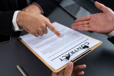 Kapanış toplantısı, iş adamı sözleşmenin şartlarını ve şartlarını dikkatle gözden geçiriyor. Şirket avukatı sözleşme anlaşmasında danışmanlık yapar. Coşkulu